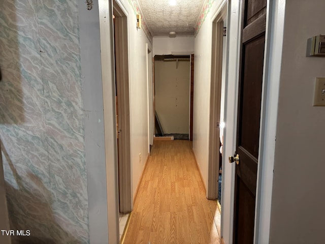 hall with light hardwood / wood-style flooring, a textured ceiling, and ornamental molding