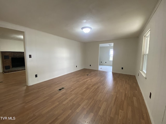 spare room featuring dark hardwood / wood-style flooring and a brick fireplace