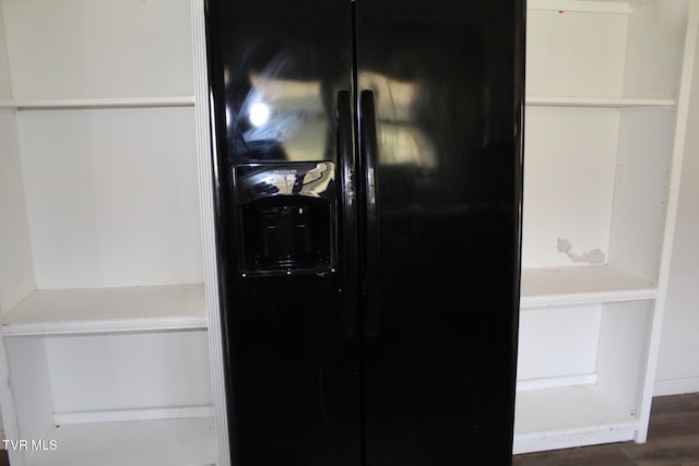 interior details with black fridge with ice dispenser and dark hardwood / wood-style flooring