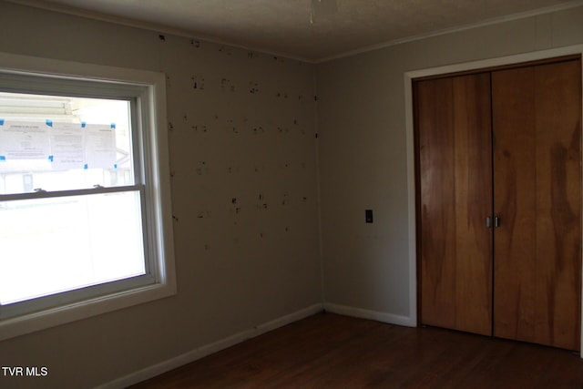 unfurnished bedroom with dark hardwood / wood-style floors, a closet, and ornamental molding