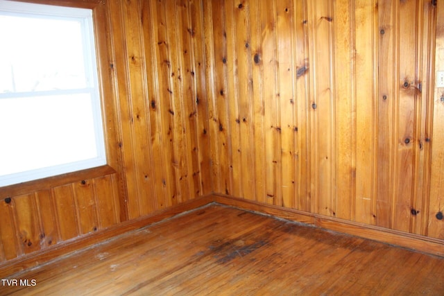 unfurnished room featuring hardwood / wood-style flooring and wooden walls