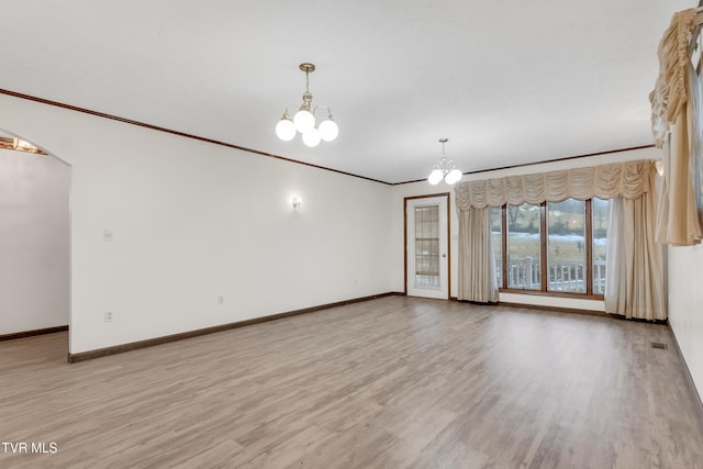 empty room with crown molding, light hardwood / wood-style floors, and a notable chandelier