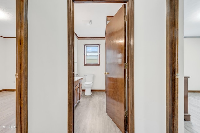 bathroom with toilet, vanity, ornamental molding, and hardwood / wood-style flooring