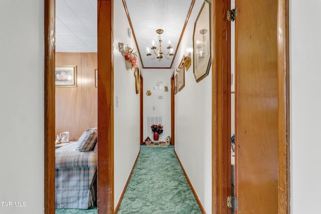 hall with carpet floors, crown molding, wooden walls, and an inviting chandelier