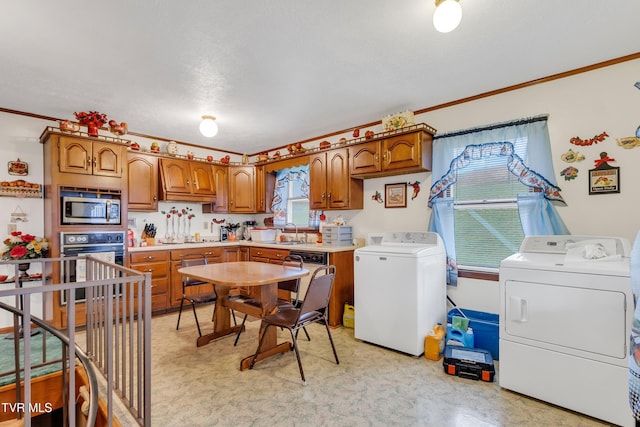 kitchen with stainless steel microwave, oven, sink, crown molding, and washing machine and clothes dryer