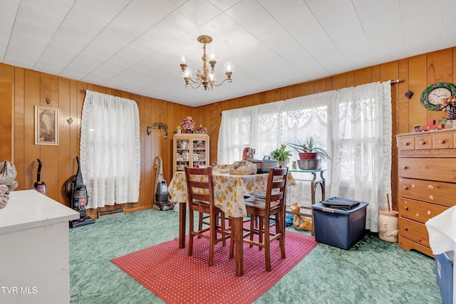 dining space featuring carpet, a notable chandelier, and wood walls