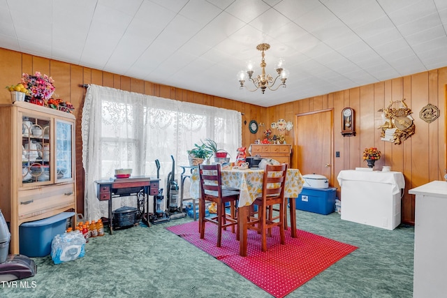 dining room featuring wood walls, dark carpet, and an inviting chandelier