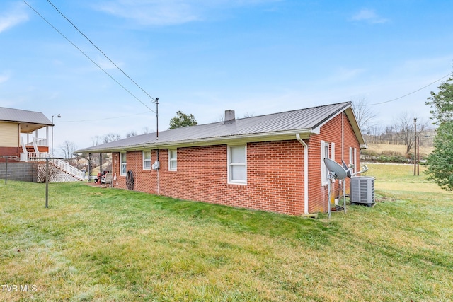 back of property featuring central AC and a lawn