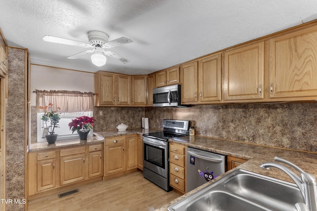 kitchen featuring a sink, visible vents, appliances with stainless steel finishes, light wood-type flooring, and tasteful backsplash