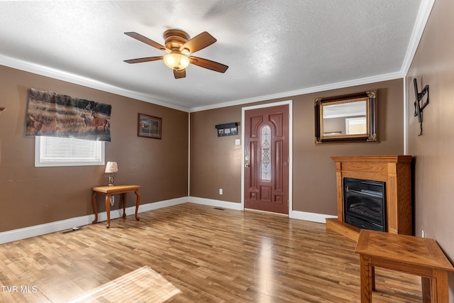 entryway featuring baseboards, ornamental molding, wood finished floors, and a glass covered fireplace