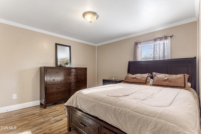 bedroom featuring baseboards, crown molding, and light wood finished floors