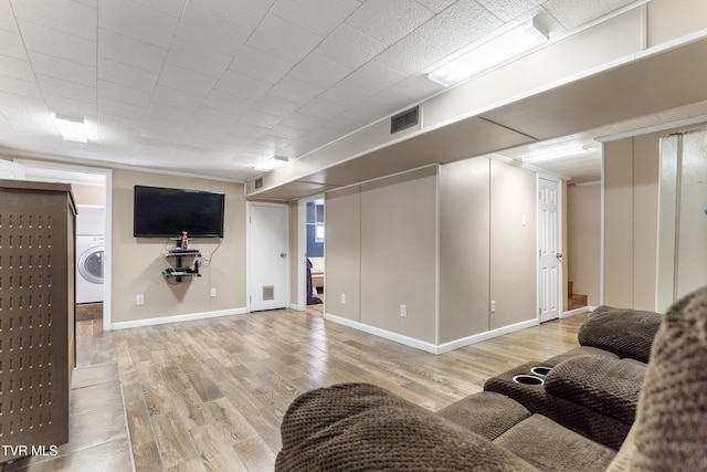 living room with washer / clothes dryer, light wood-style flooring, and visible vents