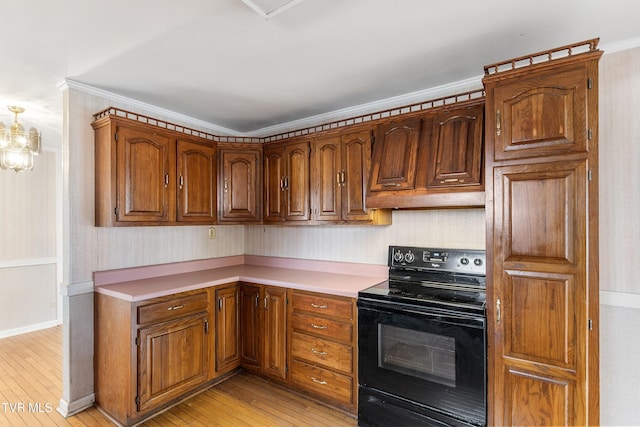 kitchen with ornamental molding, light hardwood / wood-style floors, black range with electric cooktop, and a notable chandelier