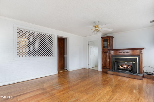 unfurnished living room featuring ornamental molding, ceiling fan, and light hardwood / wood-style floors