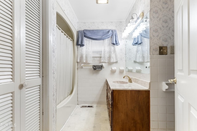 bathroom with tile walls, vanity, ornamental molding, and shower / bath combo