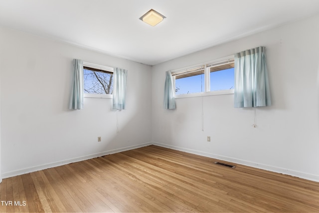 spare room featuring a wealth of natural light and light hardwood / wood-style floors