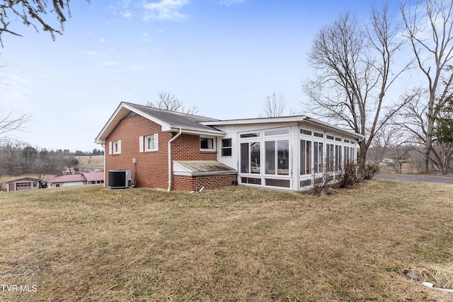 back of property with central AC unit, a yard, and a sunroom