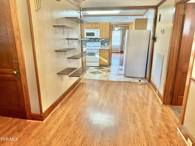 kitchen with white appliances, light hardwood / wood-style flooring, and backsplash