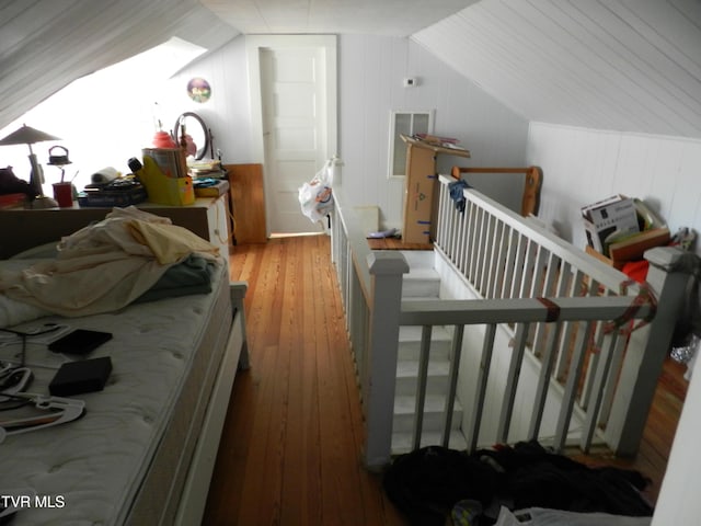 additional living space featuring vaulted ceiling with skylight, light hardwood / wood-style floors, and wood walls