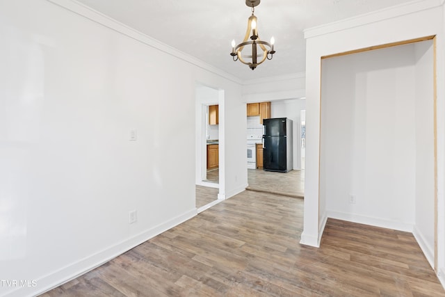 unfurnished dining area with wood-type flooring, ornamental molding, and an inviting chandelier