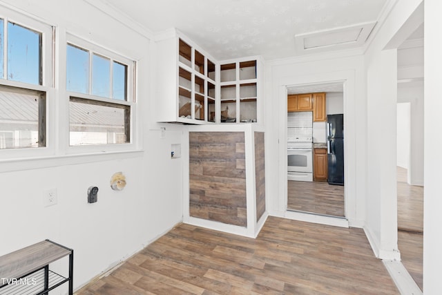 kitchen featuring crown molding, stove, decorative backsplash, black refrigerator, and hardwood / wood-style flooring