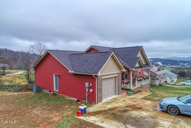 view of front of property featuring a front lawn, cooling unit, a mountain view, a porch, and a garage