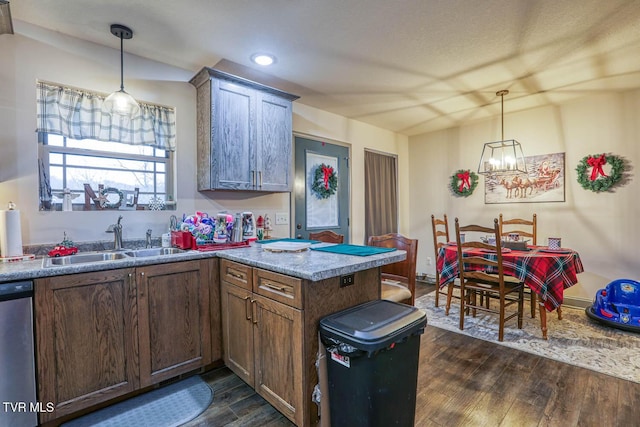 kitchen featuring pendant lighting, stainless steel dishwasher, sink, and dark wood-type flooring