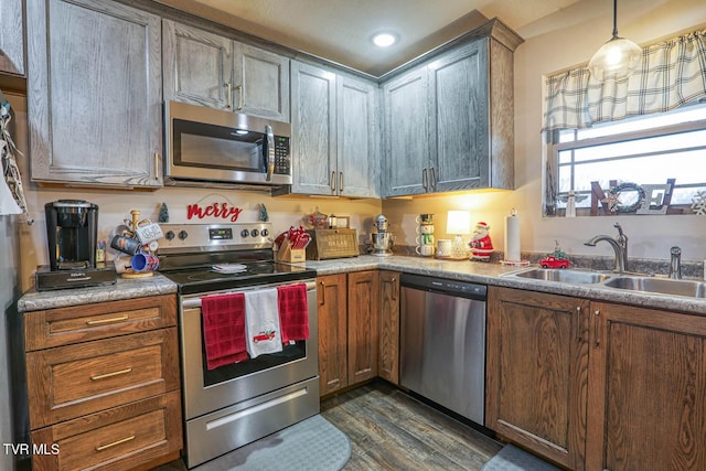 kitchen featuring dark hardwood / wood-style flooring, sink, stainless steel appliances, and decorative light fixtures