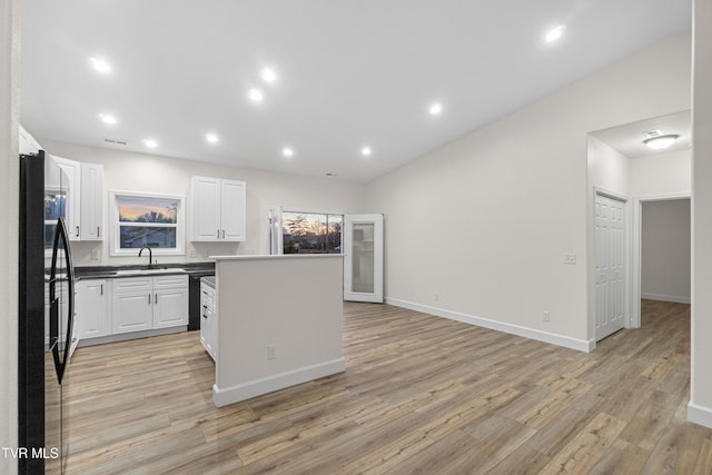 kitchen featuring sink, light hardwood / wood-style flooring, vaulted ceiling, white cabinets, and black appliances