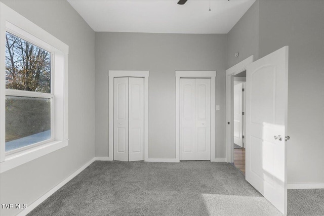 unfurnished bedroom with carpet, two closets, and ceiling fan