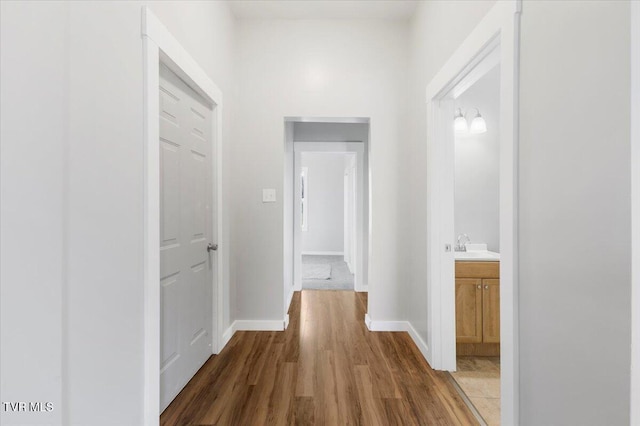 corridor with wood-type flooring and sink