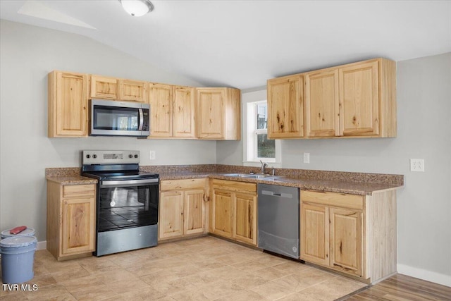 kitchen with light brown cabinetry, sink, lofted ceiling, and appliances with stainless steel finishes