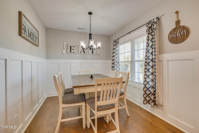 dining room with wood-type flooring and an inviting chandelier