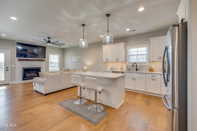 kitchen with decorative light fixtures, a center island, stainless steel appliances, and white cabinetry