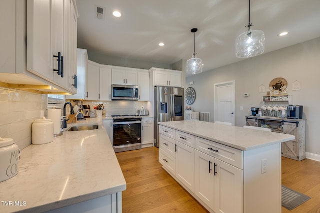 kitchen featuring a center island, white cabinets, sink, hanging light fixtures, and stainless steel appliances