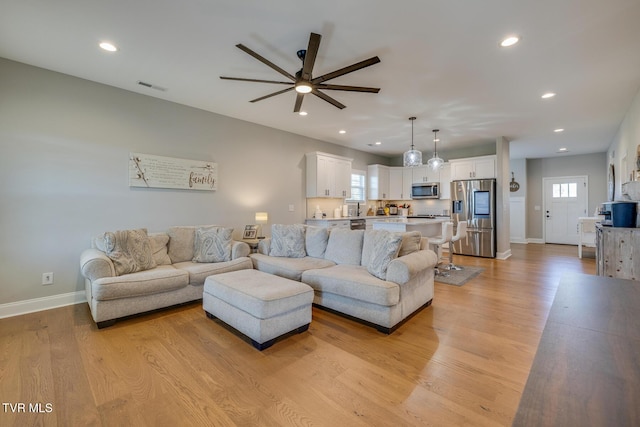 living room featuring ceiling fan and light wood-type flooring