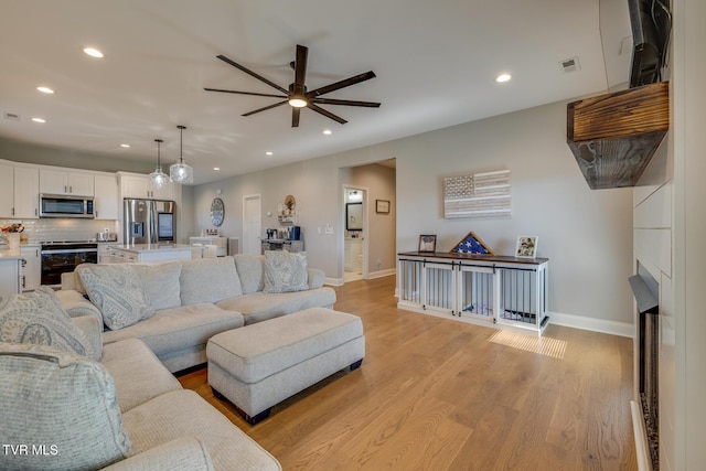 living room with ceiling fan and light wood-type flooring