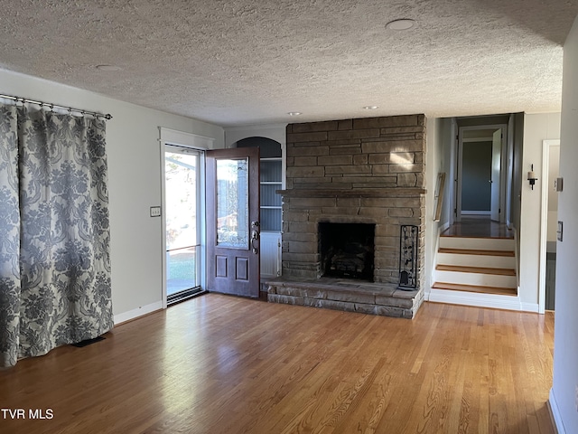 unfurnished living room with a fireplace, wood-type flooring, and a textured ceiling