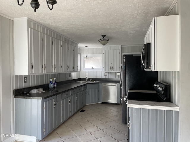 kitchen with appliances with stainless steel finishes, a textured ceiling, sink, light tile patterned floors, and gray cabinets