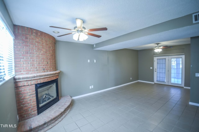 unfurnished living room with tile patterned floors, a textured ceiling, a brick fireplace, and ceiling fan