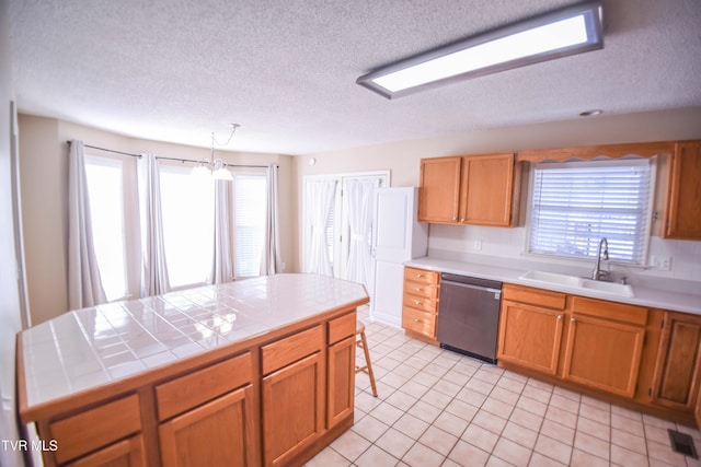 kitchen with stainless steel dishwasher, hanging light fixtures, sink, a chandelier, and tile counters