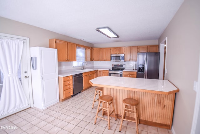 kitchen with a textured ceiling, a kitchen bar, sink, and appliances with stainless steel finishes