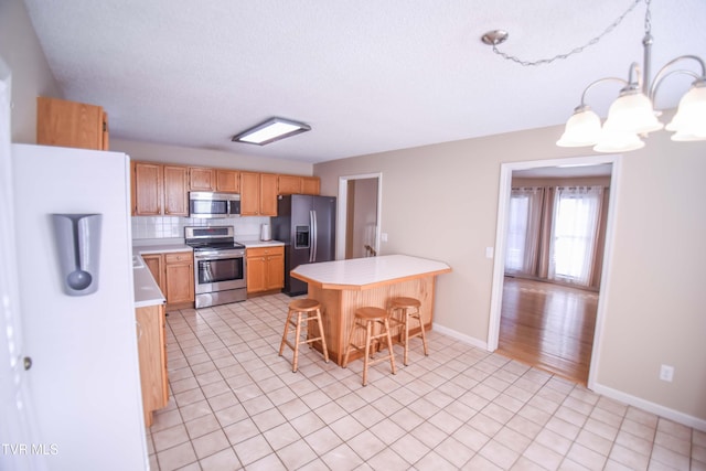 kitchen with stainless steel appliances, an inviting chandelier, backsplash, pendant lighting, and a breakfast bar