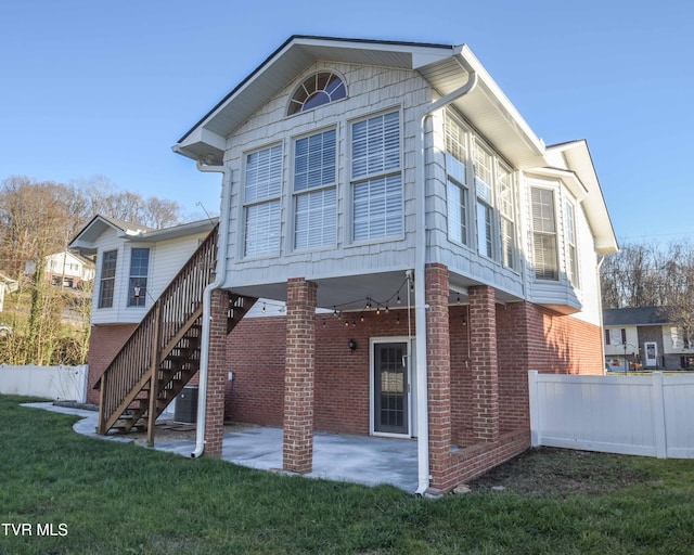 back of property with a lawn and a patio