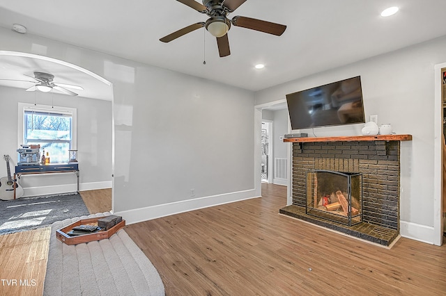 living room with a fireplace, hardwood / wood-style floors, and ceiling fan