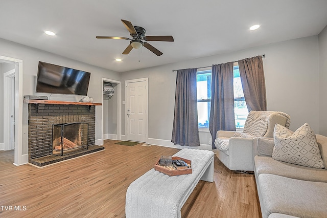 living room featuring hardwood / wood-style floors, a brick fireplace, and ceiling fan