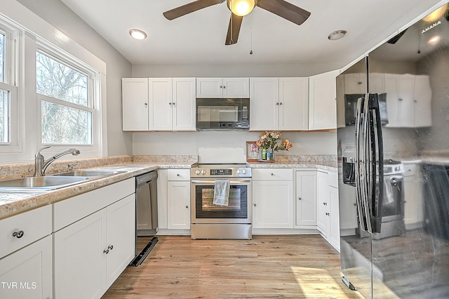 kitchen featuring white cabinets, sink, light hardwood / wood-style flooring, ceiling fan, and stainless steel appliances