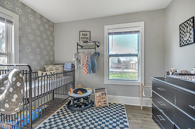 bedroom with hardwood / wood-style flooring and a crib