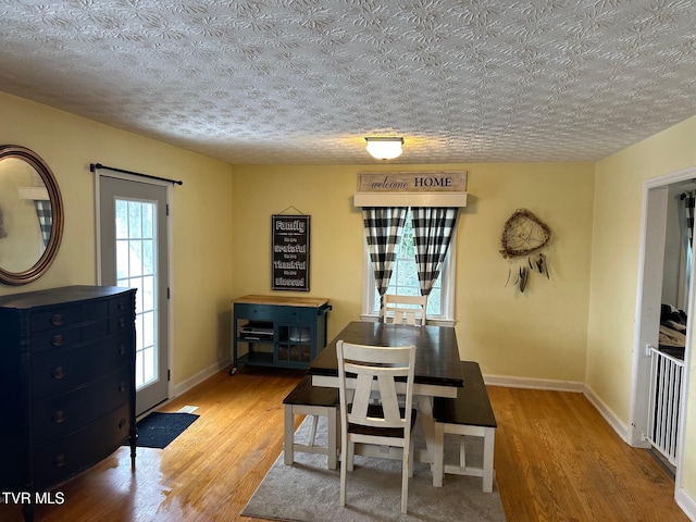 dining area featuring light wood-type flooring and a textured ceiling