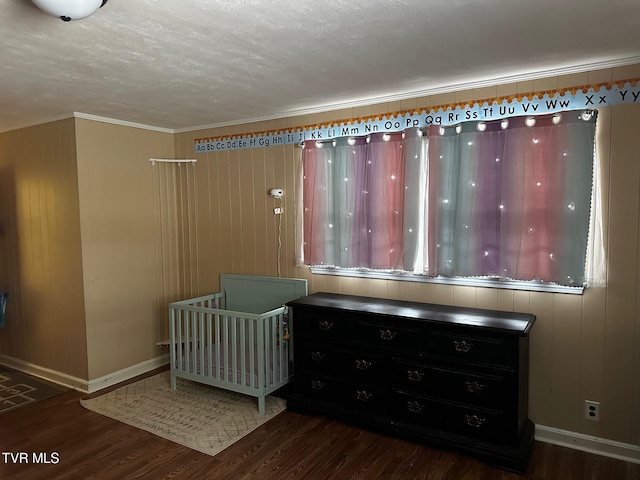 unfurnished bedroom featuring crown molding, a crib, and dark wood-type flooring